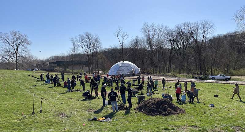 Volunteers planting fruit trees at Mimi's Pantry to kick off community greening projects around the NFL Draft.